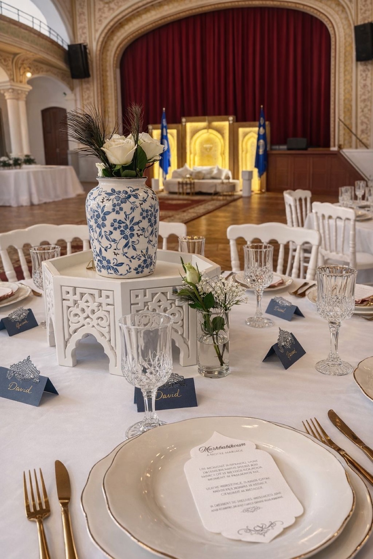 Table élégante avec marque-places bleus, fleurs blanches, verres en cristal et couverts dorés