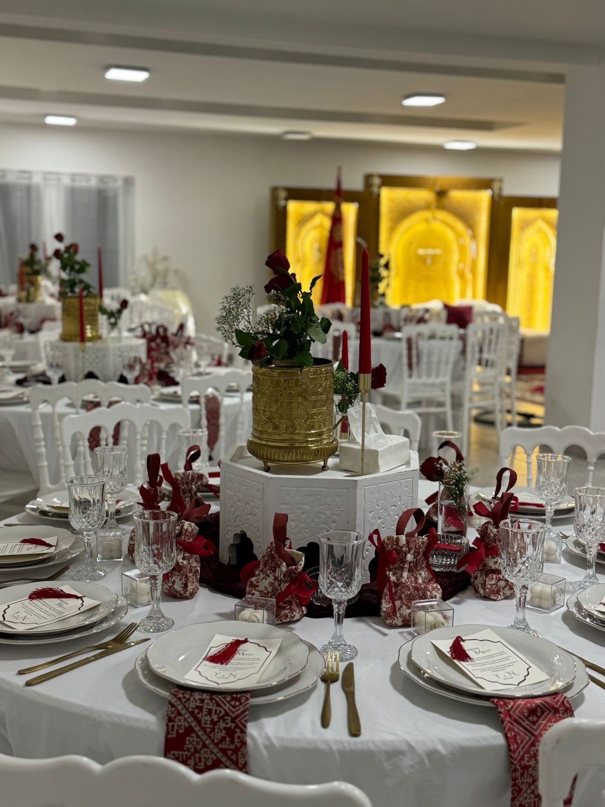Centre de table rouge et doré avec bougies, roses, verrerie et menus personnalisés